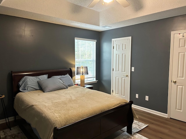 bedroom featuring ceiling fan, dark wood-type flooring, and a textured ceiling