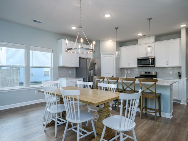 dining room with dark hardwood / wood-style floors, plenty of natural light, an inviting chandelier, and sink