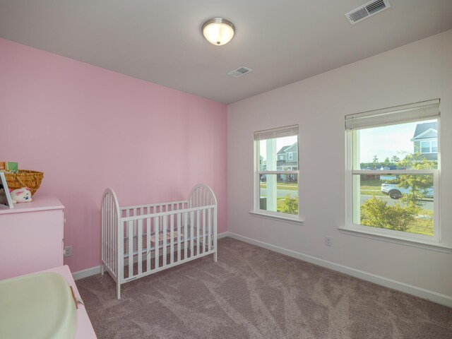 bedroom featuring a nursery area and carpet floors