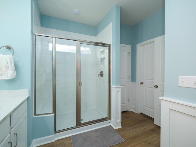 bathroom featuring wood-type flooring, a shower with door, and vanity