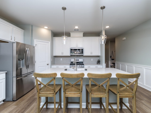 kitchen with appliances with stainless steel finishes, hardwood / wood-style flooring, and hanging light fixtures