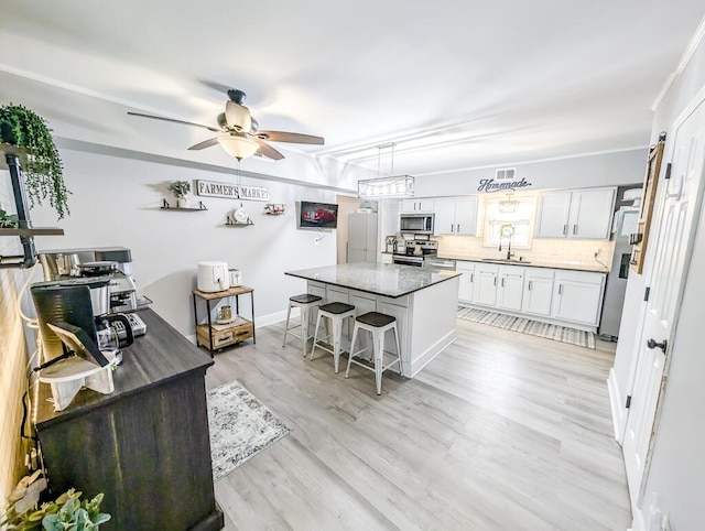 kitchen featuring a center island, a kitchen bar, white cabinetry, appliances with stainless steel finishes, and sink