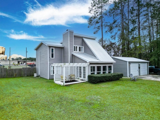 rear view of property with a garage, french doors, an outbuilding, and a yard