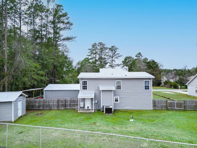 rear view of house with central AC unit, a shed, and a lawn