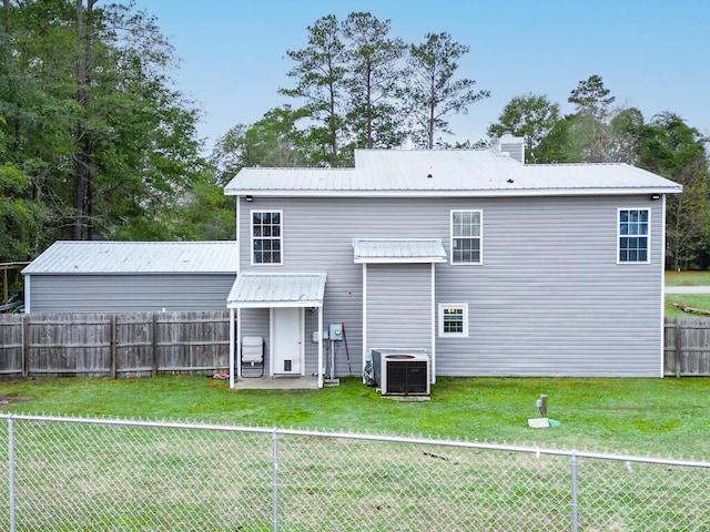 rear view of house featuring central air condition unit and a lawn