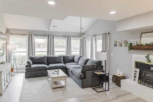 living room featuring lofted ceiling, a fireplace, and light wood-type flooring