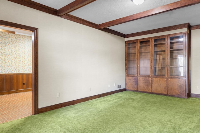 unfurnished room featuring a textured ceiling, beamed ceiling, visible vents, baseboards, and carpet