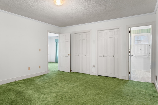 unfurnished bedroom featuring carpet flooring, two closets, baseboards, ornamental molding, and a textured ceiling