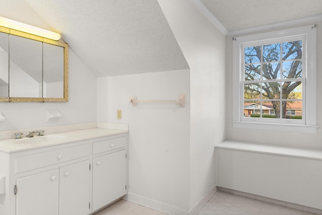 bathroom featuring vaulted ceiling, vanity, baseboards, a textured ceiling, and crown molding