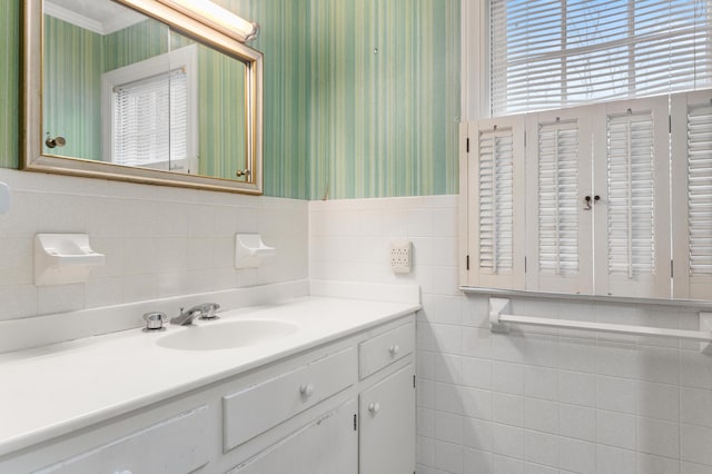 bathroom featuring vanity, crown molding, wallpapered walls, and tile walls