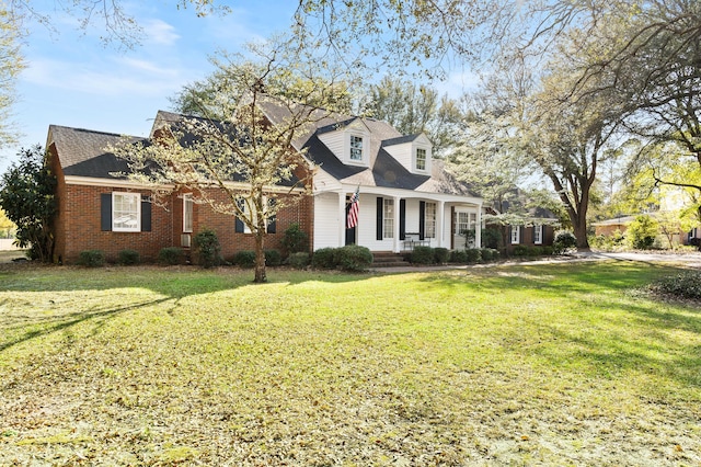 cape cod home featuring brick siding, a porch, a shingled roof, and a front lawn