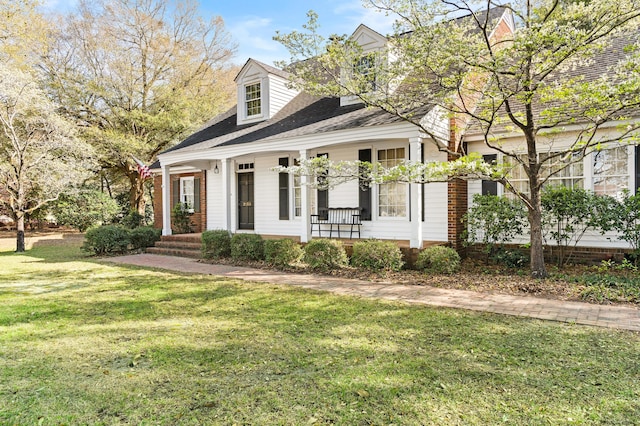 cape cod-style house featuring covered porch and a front lawn