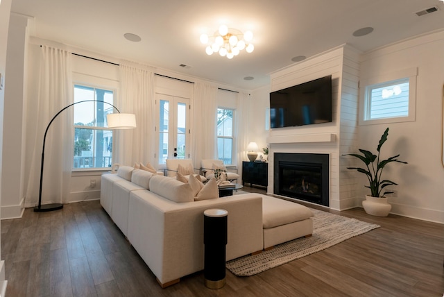 living room with crown molding, a large fireplace, and dark hardwood / wood-style floors