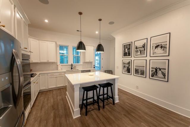 kitchen with appliances with stainless steel finishes, tasteful backsplash, white cabinets, ornamental molding, and a center island