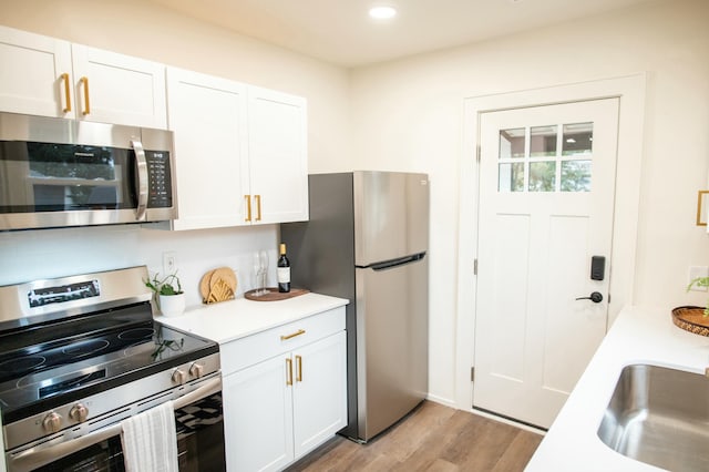 kitchen with sink, white cabinets, stainless steel appliances, and light wood-type flooring