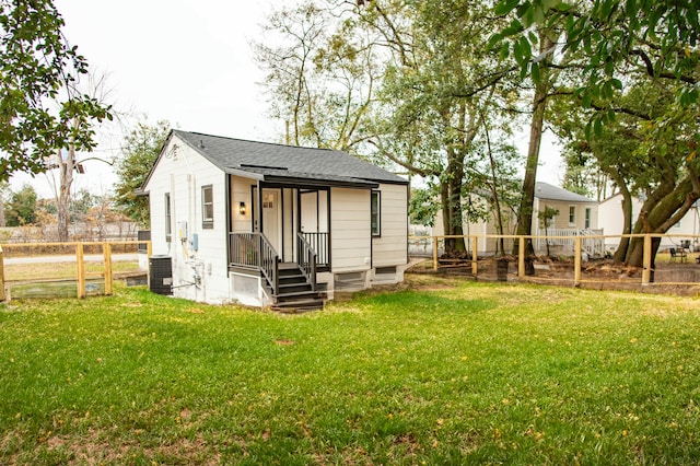 rear view of house with a yard and central AC