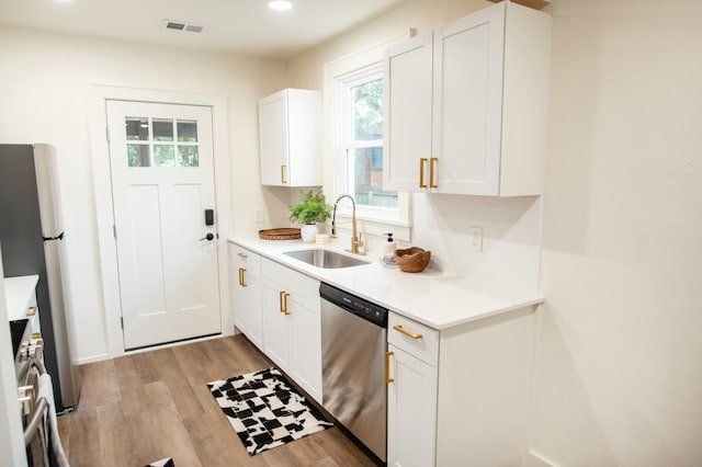 kitchen with backsplash, white cabinets, sink, light wood-type flooring, and stainless steel appliances