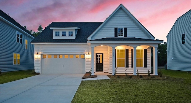 view of front facade featuring driveway, a porch, a lawn, and an attached garage