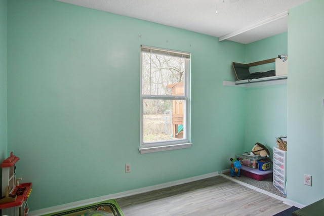 interior space featuring a textured ceiling, baseboards, and wood finished floors