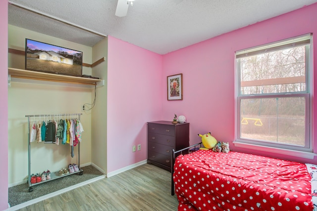 bedroom featuring a textured ceiling, wood finished floors, a ceiling fan, and baseboards