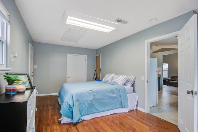 bedroom featuring visible vents, vaulted ceiling, baseboards, and wood finished floors