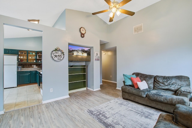 unfurnished living room with vaulted ceiling, ceiling fan, light wood finished floors, and visible vents