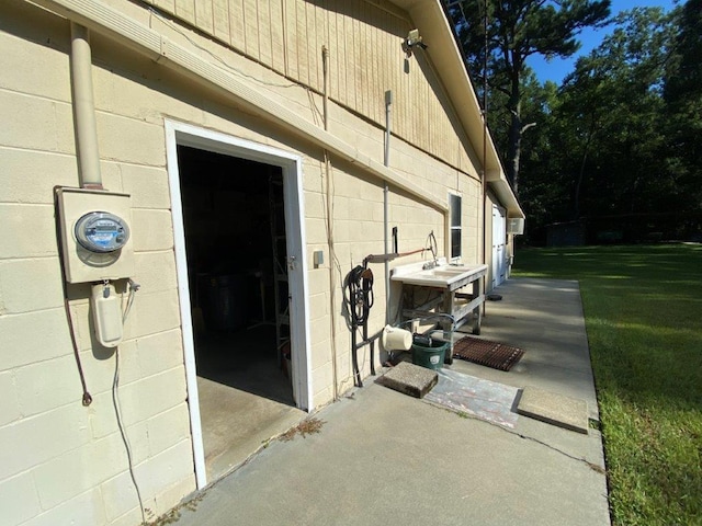 view of exterior entry with a yard and a patio area