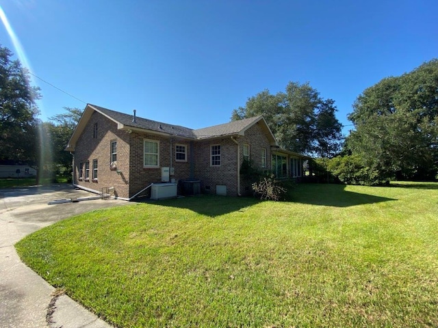 view of side of home with cooling unit and a lawn