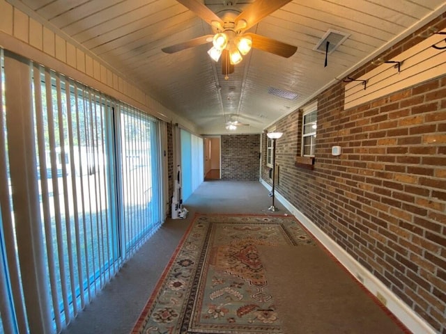 hallway featuring wood ceiling and brick wall