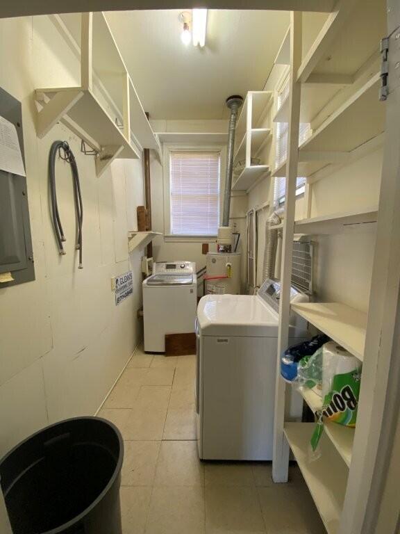 laundry room with electric water heater, light tile patterned floors, and washer and clothes dryer