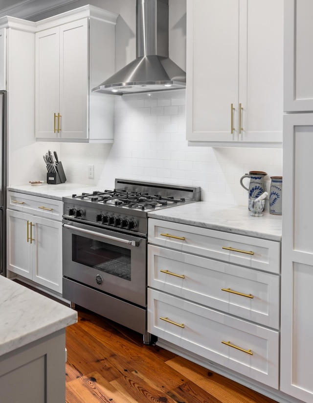 kitchen with white cabinetry, wall chimney range hood, stainless steel stove, and light stone countertops