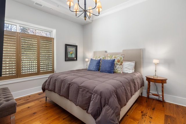 bedroom with a notable chandelier and wood-type flooring