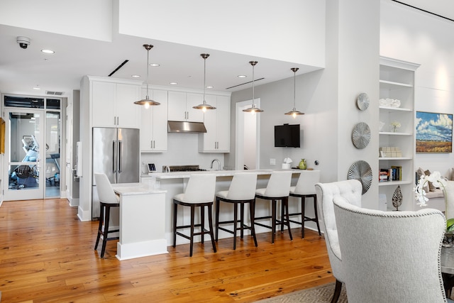 kitchen with hanging light fixtures, white cabinetry, a breakfast bar area, and light hardwood / wood-style floors