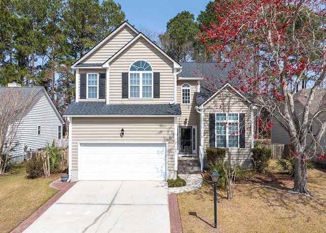 traditional-style house featuring a front lawn, an attached garage, driveway, and roof with shingles