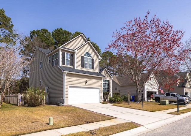 traditional-style house with a front yard, an attached garage, fence, and driveway