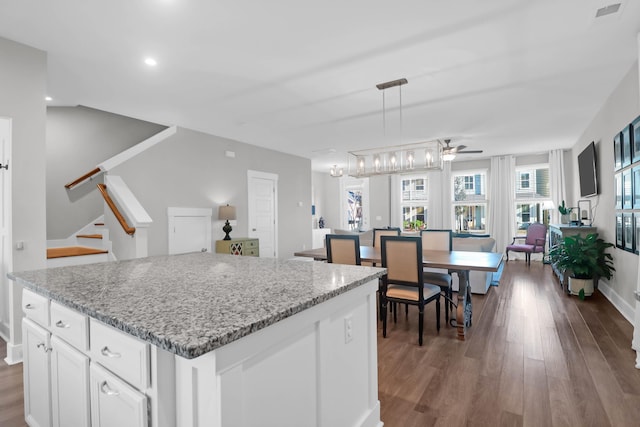 kitchen with white cabinets, a kitchen island, a ceiling fan, and wood finished floors