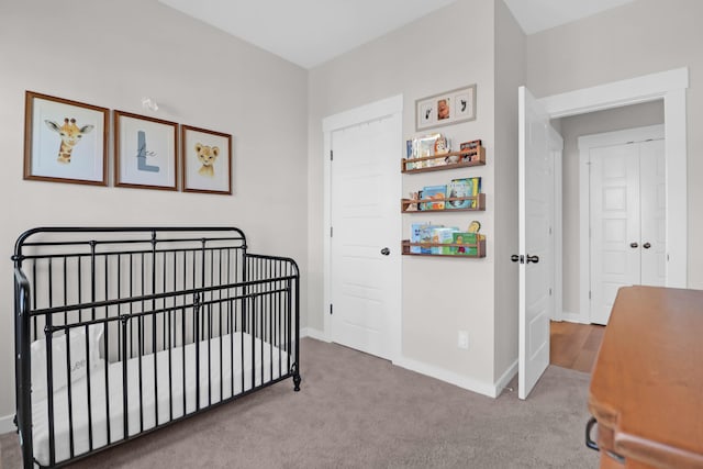 carpeted bedroom featuring baseboards and a crib