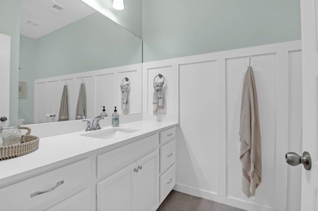 bathroom featuring visible vents, toilet, a decorative wall, tile patterned flooring, and vanity