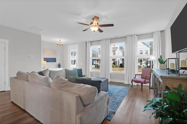 living area featuring ceiling fan with notable chandelier and wood finished floors