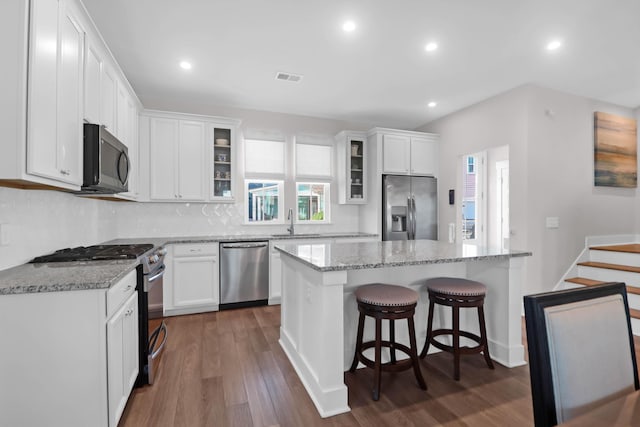 kitchen featuring visible vents, a sink, white cabinets, appliances with stainless steel finishes, and a center island