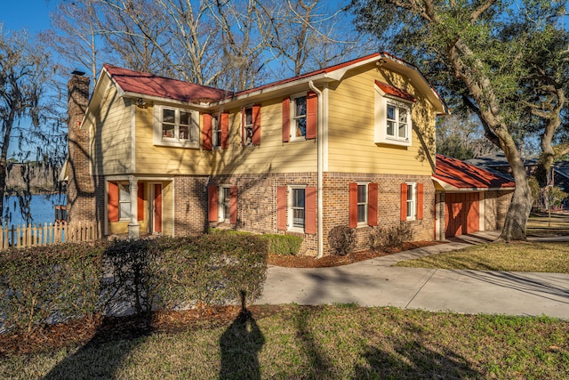 view of front of property with an attached garage, driveway, a chimney, and brick siding