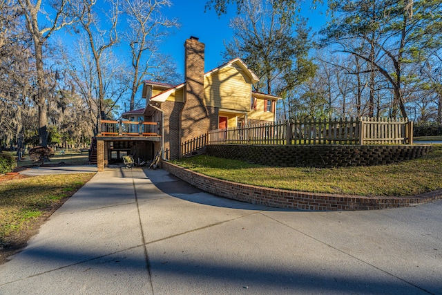 view of side of property with brick siding, a lawn, a chimney, and a wooden deck