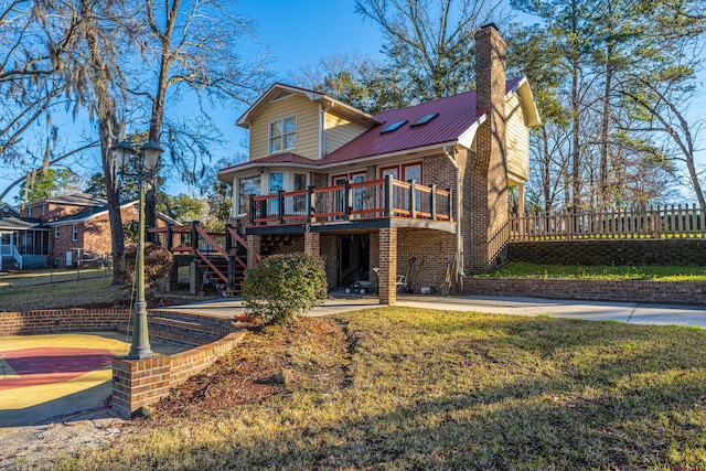 back of property with a lawn, metal roof, stairs, a deck, and brick siding