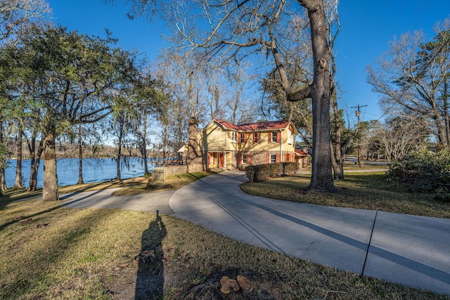 view of street with a water view and concrete driveway