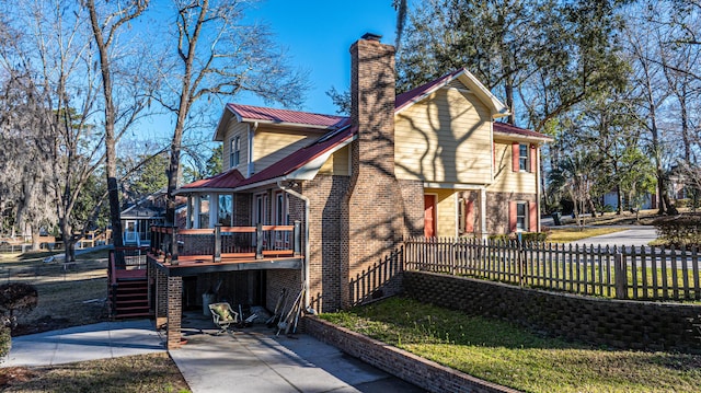 rear view of house featuring a deck, metal roof, brick siding, fence, and stairway