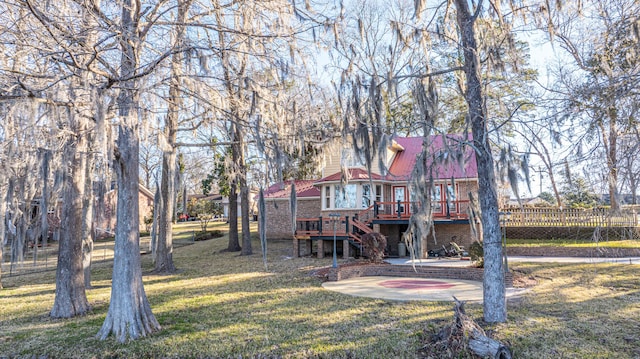 rear view of property featuring a lawn, stairway, metal roof, a deck, and brick siding