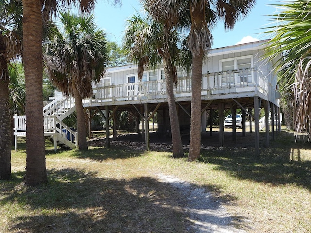 rear view of property featuring a yard, a deck, stairs, and a carport