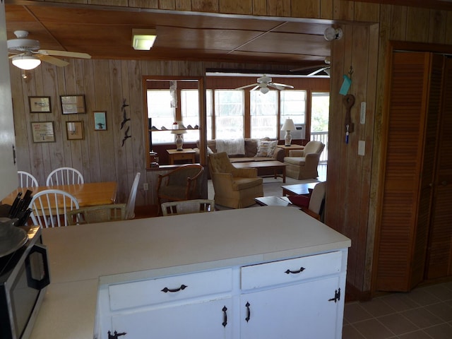 kitchen featuring wooden walls, light countertops, ceiling fan, and light tile patterned floors