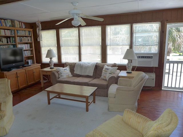 living room featuring a ceiling fan, wooden walls, and a healthy amount of sunlight