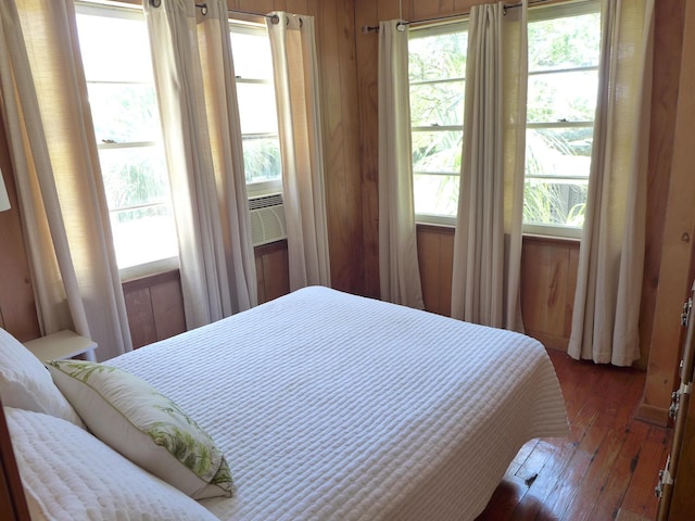 bedroom featuring wood walls, cooling unit, and hardwood / wood-style flooring
